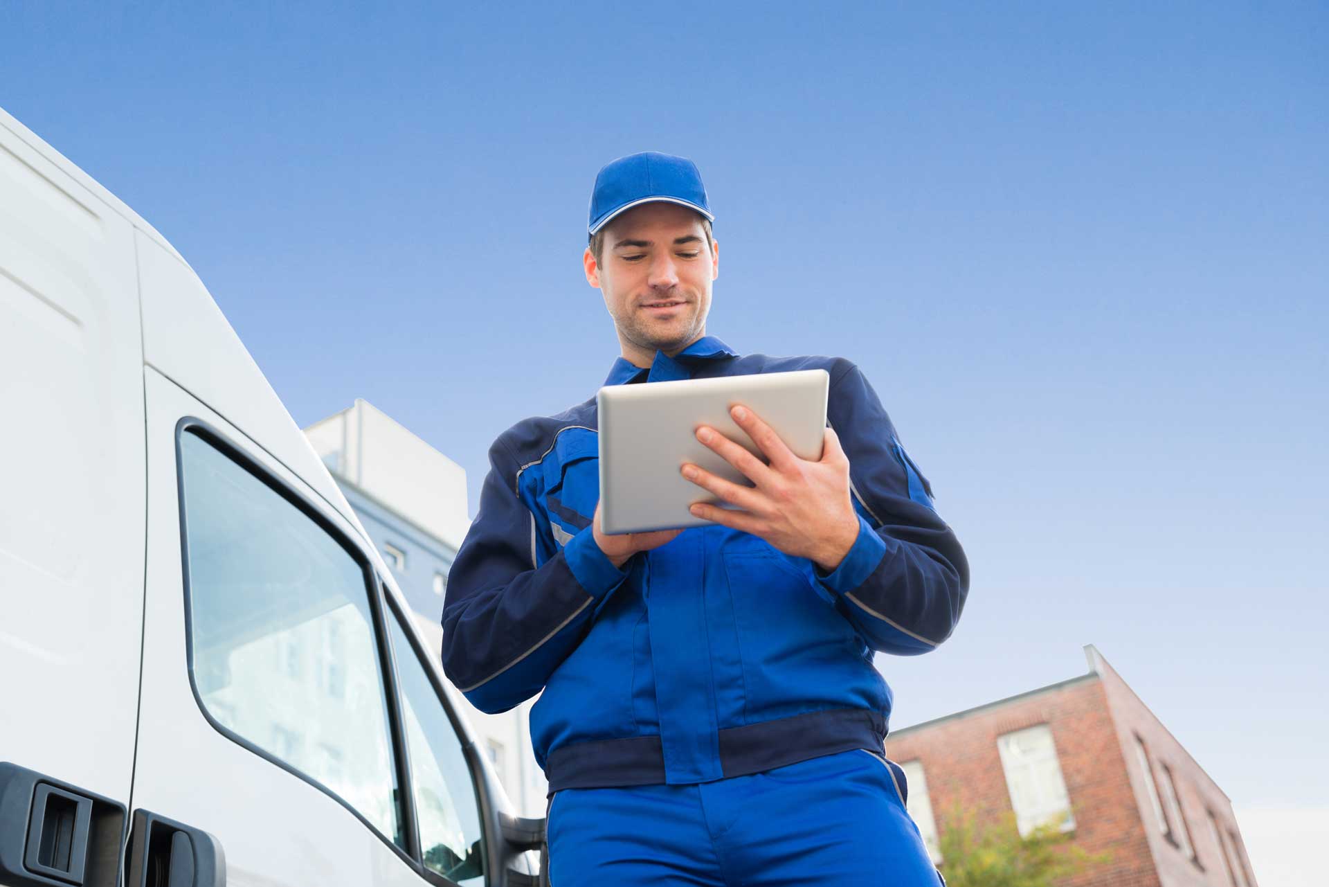 slider-image delivery-professional-using-tablet-standing-next-to-delivery-van